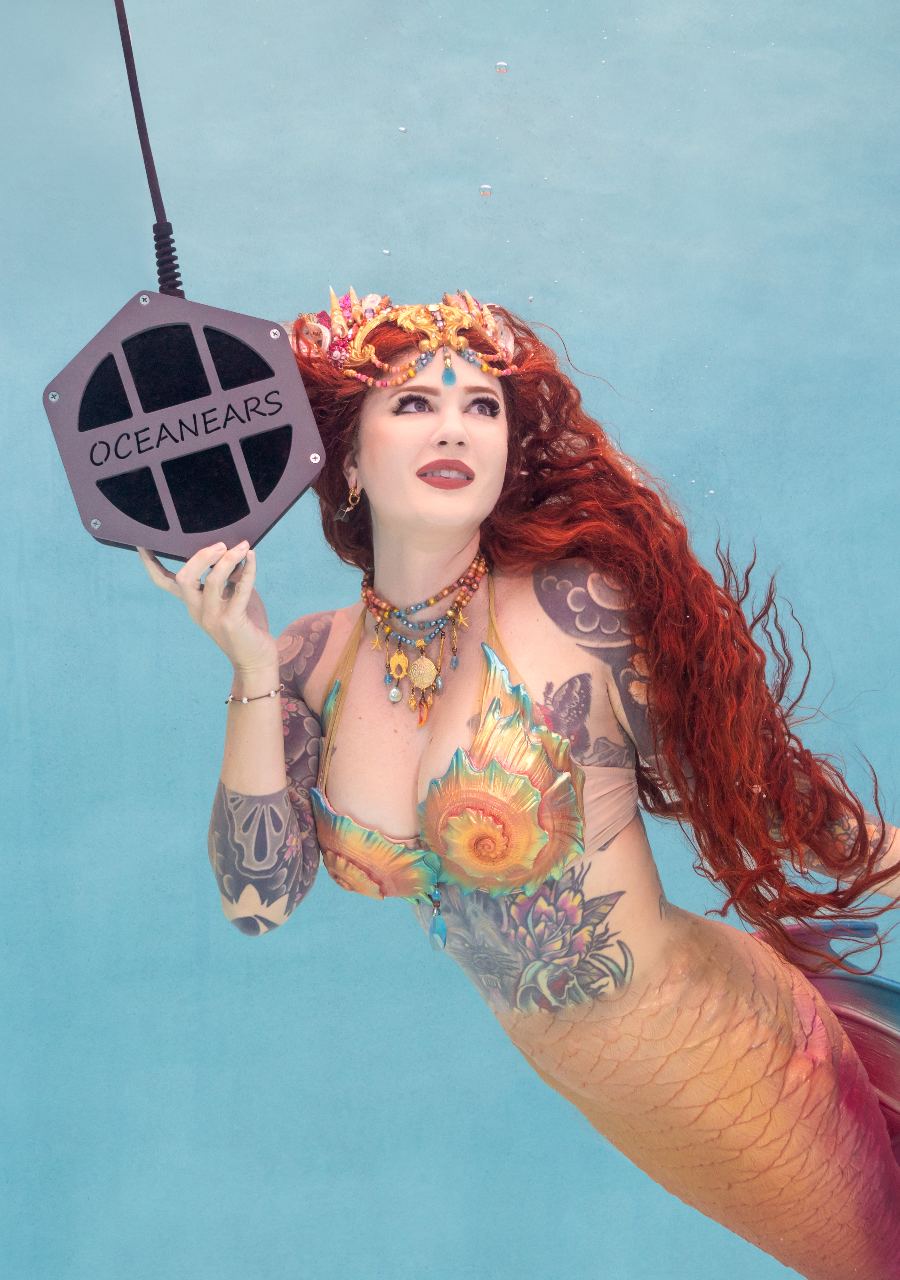 Red-haired mermaid in a colourful scaled tail swimming underwater during a Florida mermaid photoshoot