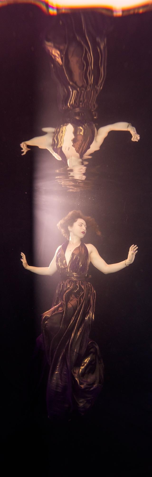 Backlit mermaid silhouette with her tail reflected in dark water