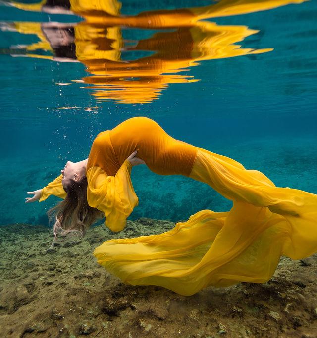 Underwater maternity photoshoot in a flowing yellow gown at a Florida spring