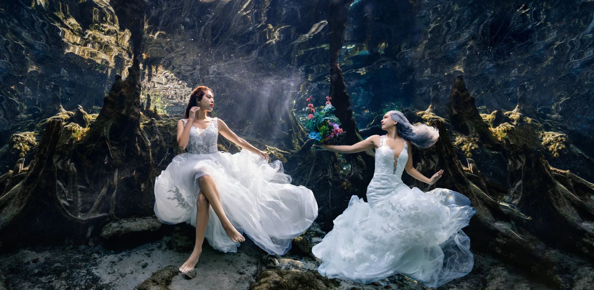 Two brides in white gowns photographed underwater in a Florida cavern