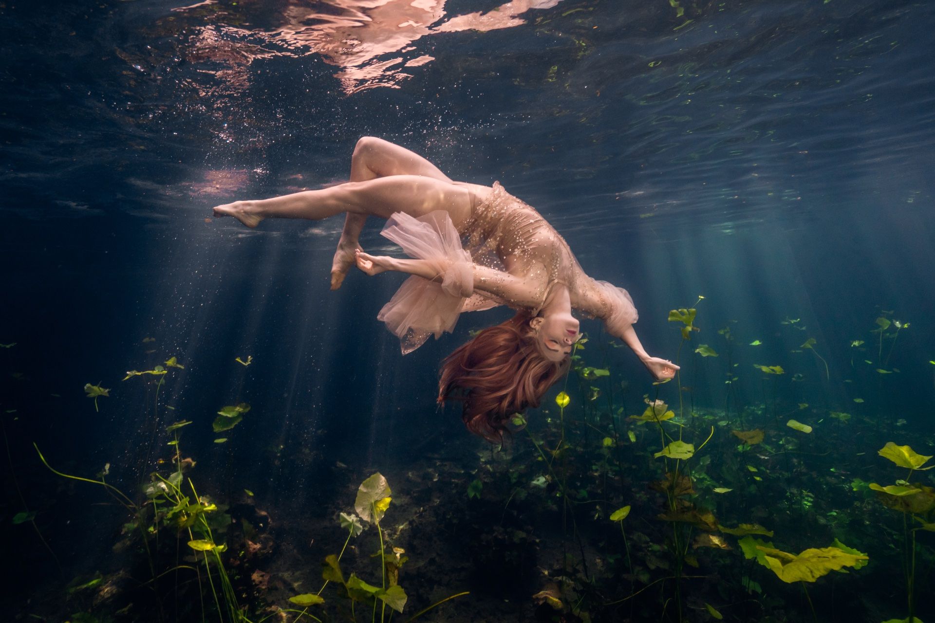 Model floating underwater in a sunlit Florida spring