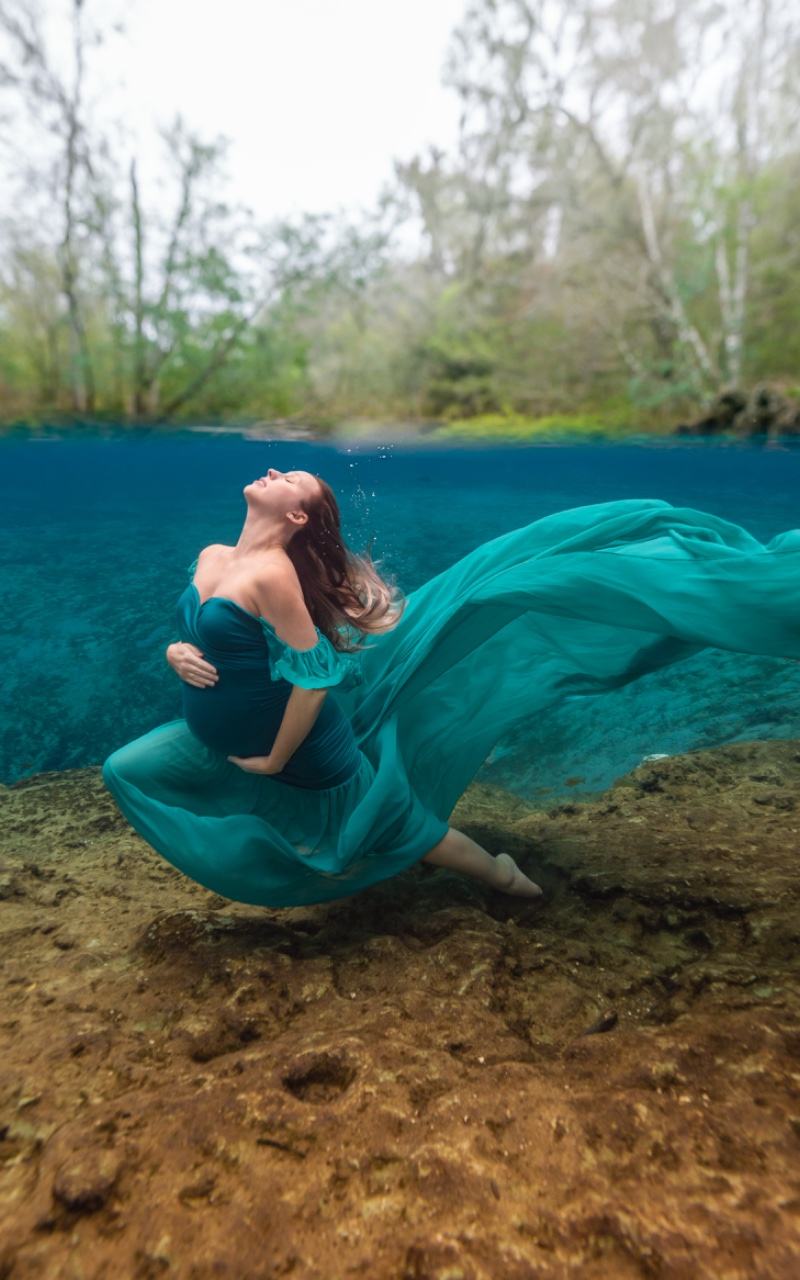 Underwater split shot of a model in a teal gown at a Florida spring