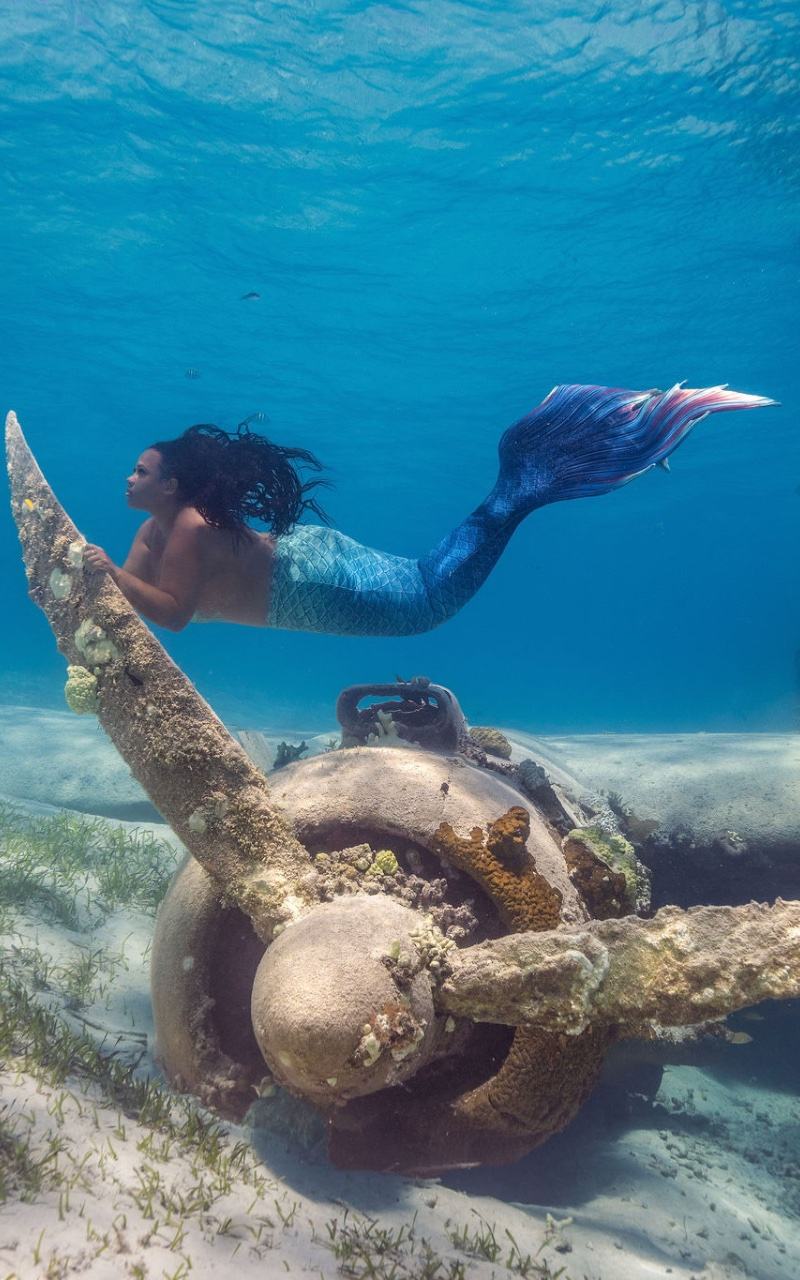 Model swimming underwater beside a sea turtle in clear blue water
