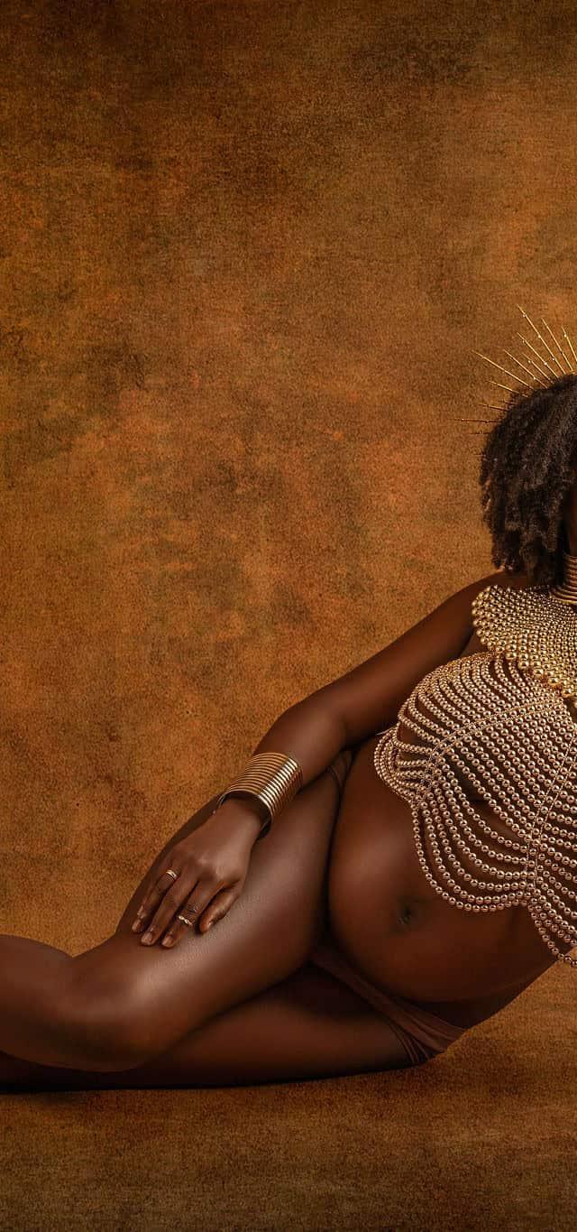 Studio maternity photoshoot with gold jewelry and warm light