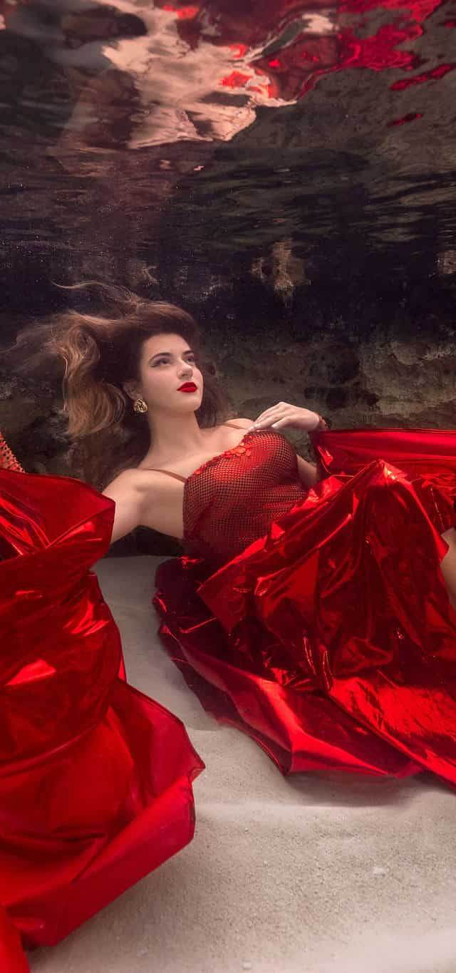 Woman wearing red dress poses underwater