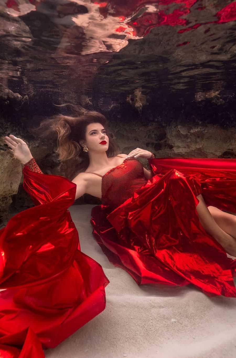 Woman wearing red dress poses underwater