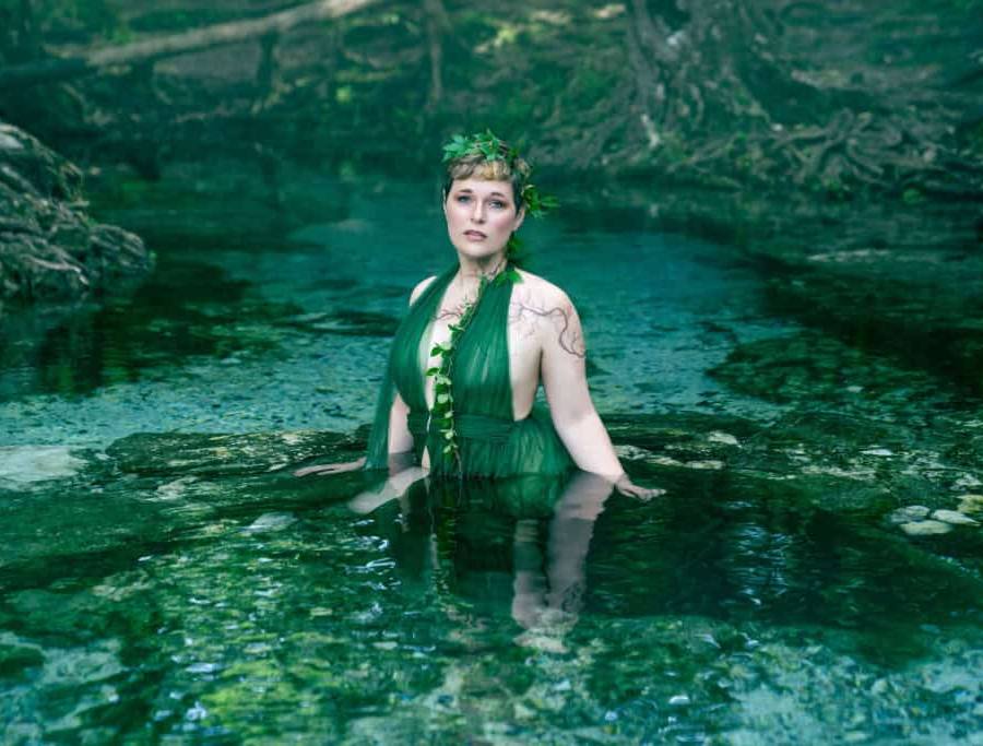 Woman wearing a green dress poses in the water at a local Florida spring