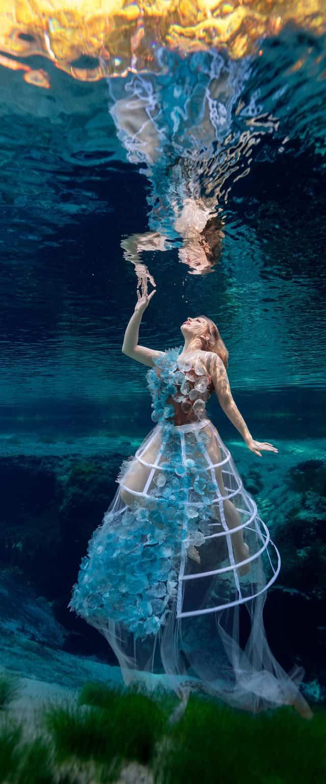 Underwater split shot of a white gown beneath the surface