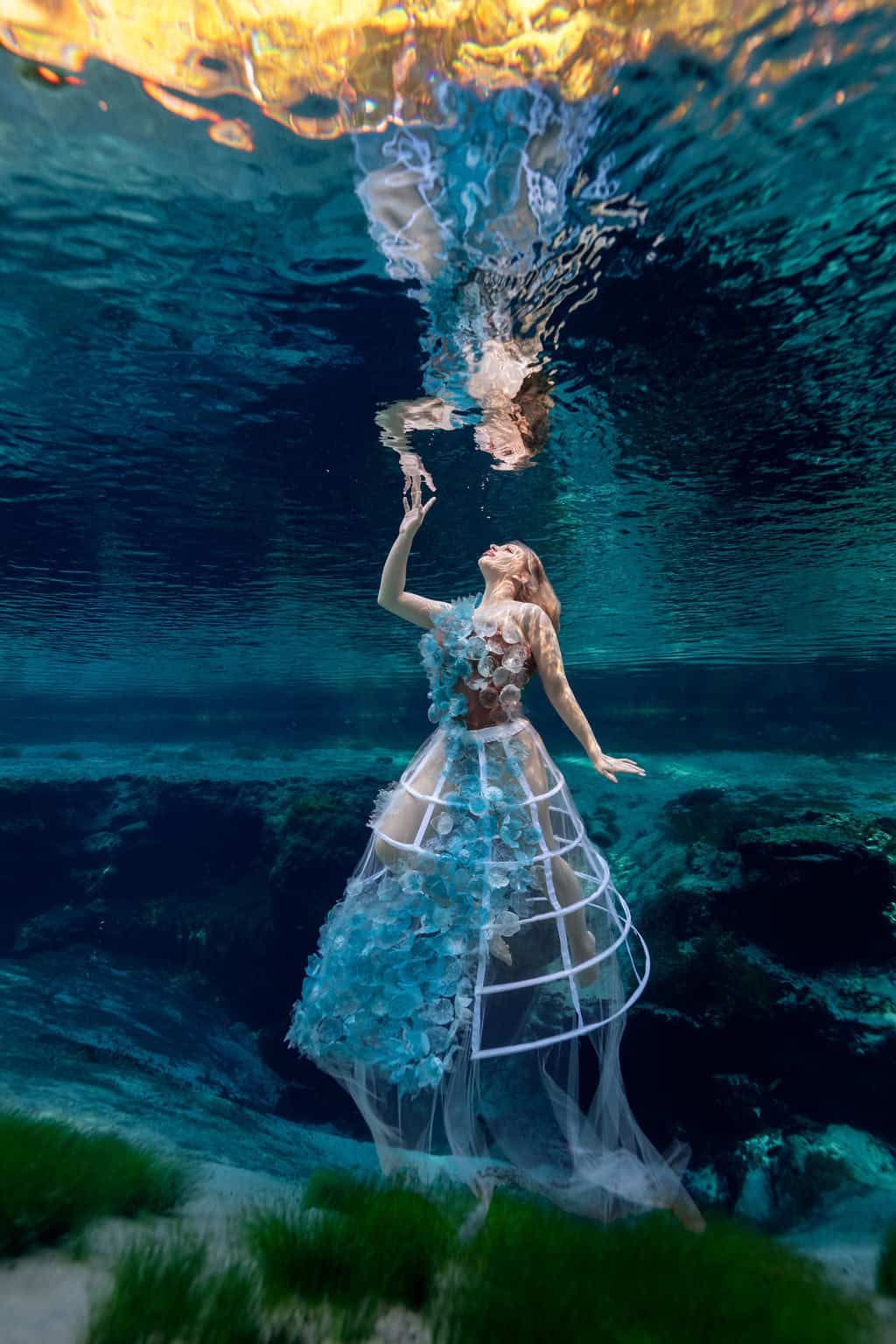 Underwater portrait in a voluminous white gown beneath the surface