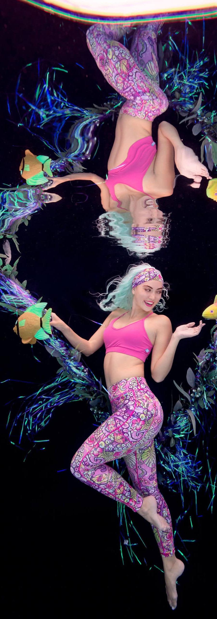 Underwater model poses with fake fish against a black backdrop for clothing company Spacefish Army.