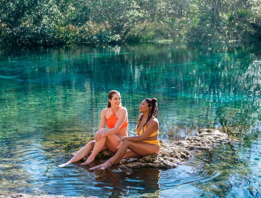 Two women friends sitting on rocks in the water at a local Florida Spring in Suwannee County.