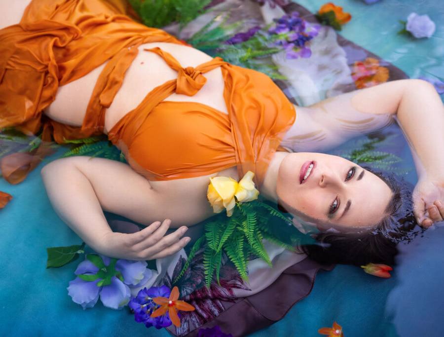 Model in orange dress posing in shallow water during modeling workshop